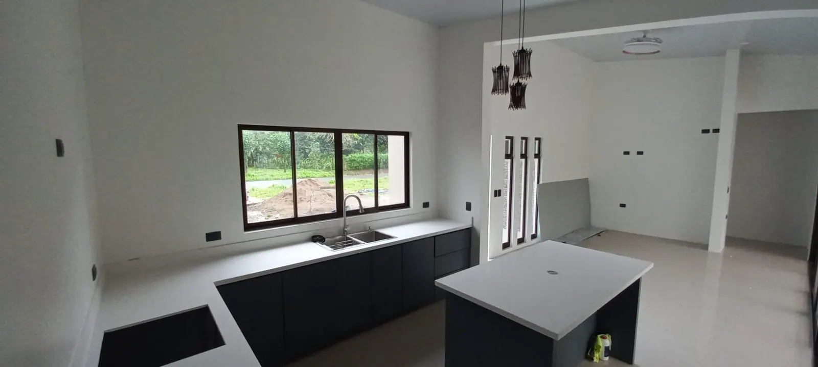 Cocina con isla blanca, ventanas y lamparas colgantes.