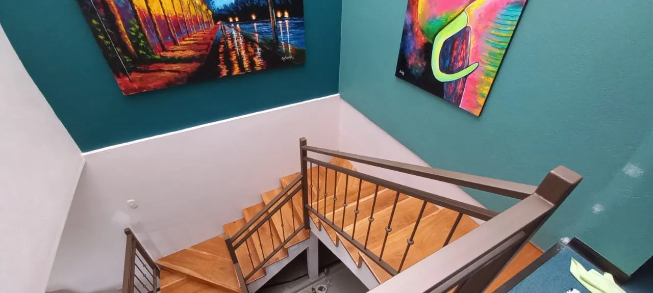 Vista superior de escaleras de madera con barandal de metal.