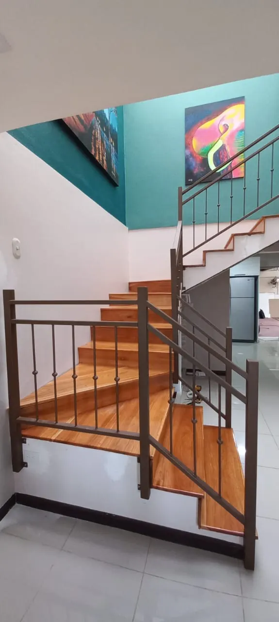 Vista inferior de escaleras de madera con barandal de metal.